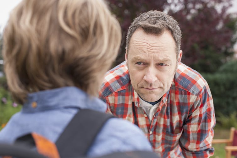 back of a child's head with man stooping to look at kid's face