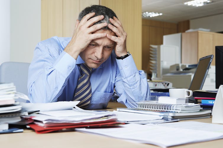 A man sitting at a desk with his head in his hands.