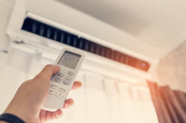 hand pointing a remote control at an aircon unit