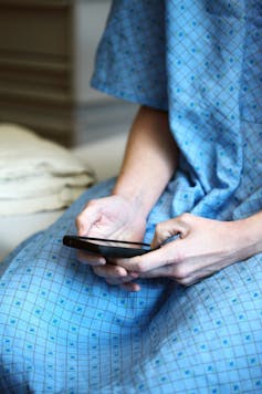 Patient sits on hospital bed, texting