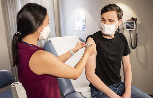 Nurse puts bandaid on patient's arm after vaccination