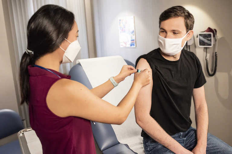 Nurse puts bandaid on patient's arm after vaccination