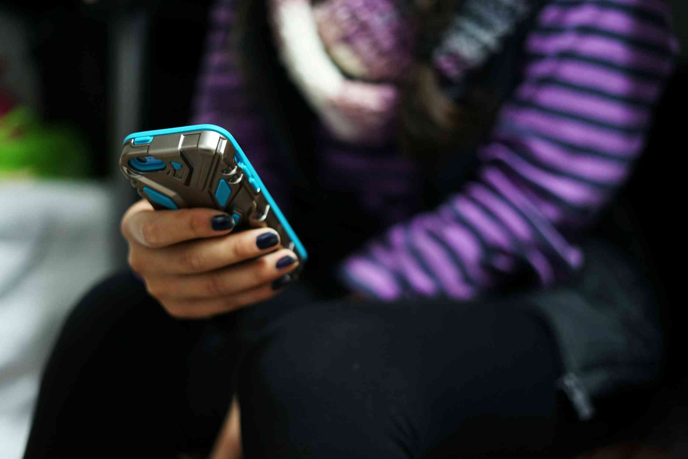 A young person holds a phone.