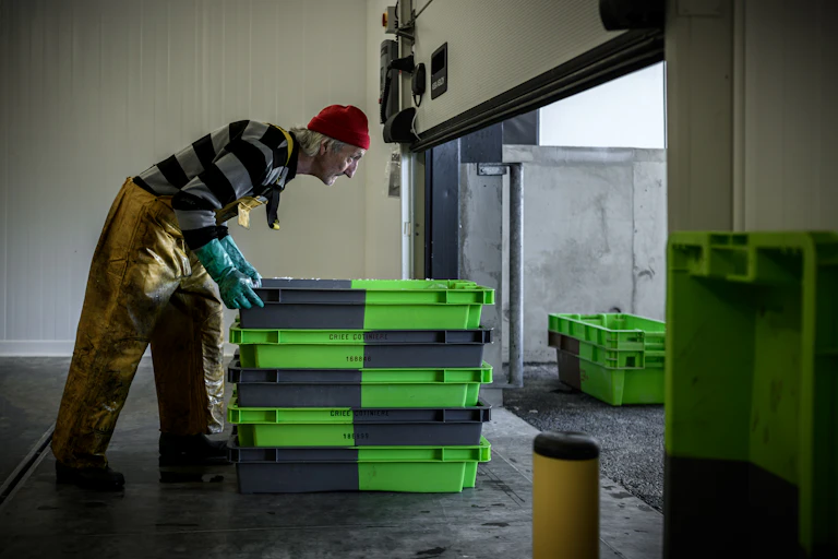 Un homme pousse des caisses de poissons