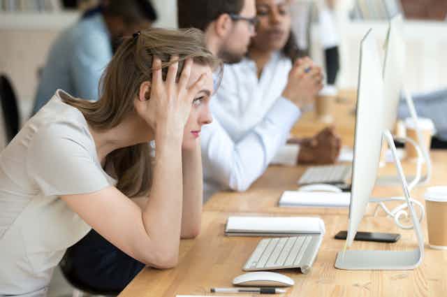 Woman looking stressed at work station.