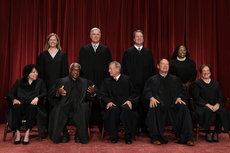 Five men and four women wearing black robes pose for a portrait.