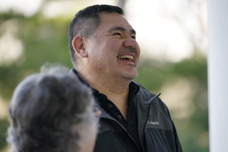 A man in a jacket smiling broadly.