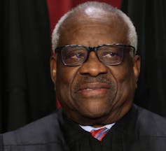 A Black man wearing a robe poses for a portrait.