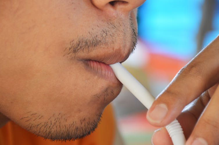 Person drinking from straw in close up