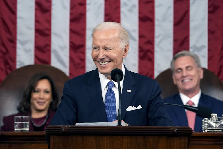 A man in blue tie and jacket in flanked by a woman and a man. All three are smiling.