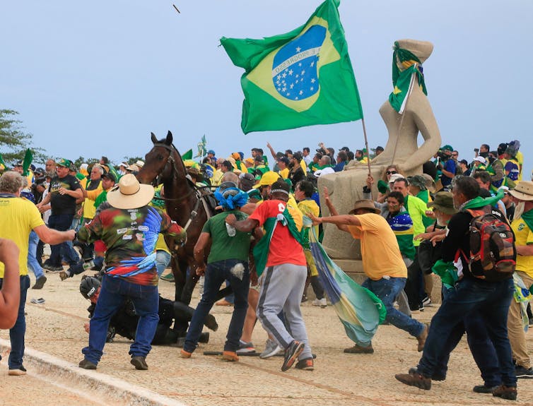 As some Brazilian flag-holding supporters of far-right ex-president Jair Bolsonaro charge him, a military police officer falls from his horse to the ground.