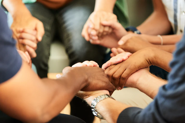 People sitting in a circle holding hands