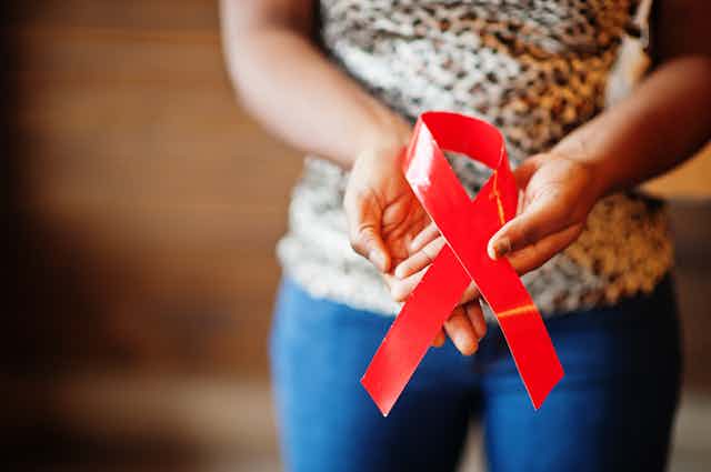 Mujer joven sujetando un lazo contra el sida.