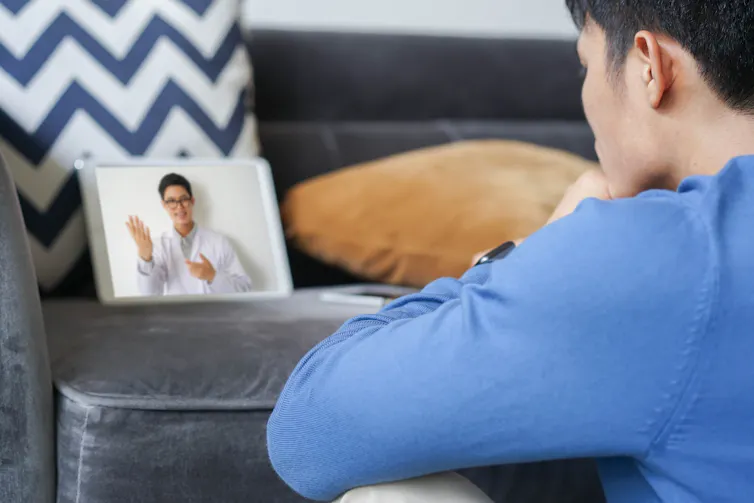Close-up rear view of young man in streaming on videocall on a tablet