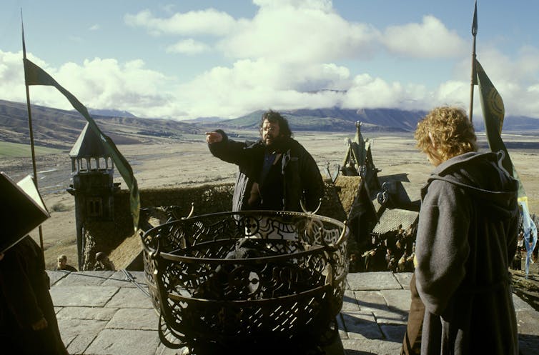 Peter Jackson directing the action on the New Zealand set of The Lord of the Rings: The Return of the King, January 2004. Mountains, sky, set of village in the background.