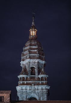 La torre de una catedral iluminada con la linterna encendida.