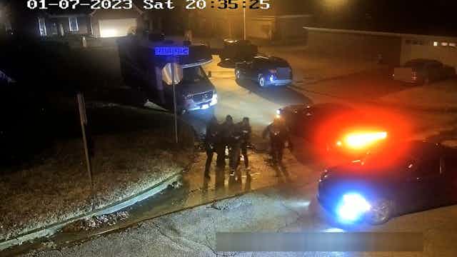 Suveillance video footage shows a groups of uniformed officers surrounding a man,