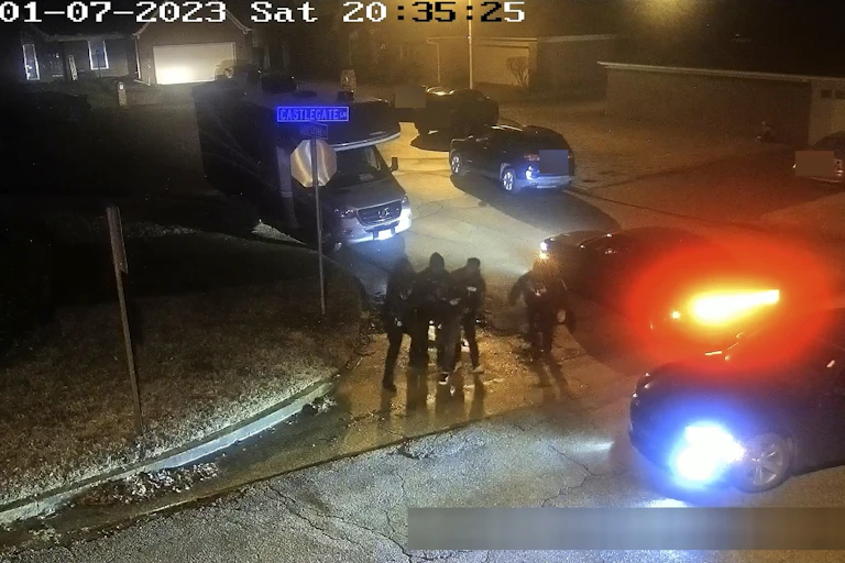 Suveillance video footage shows a groups of uniformed officers surrounding a man,