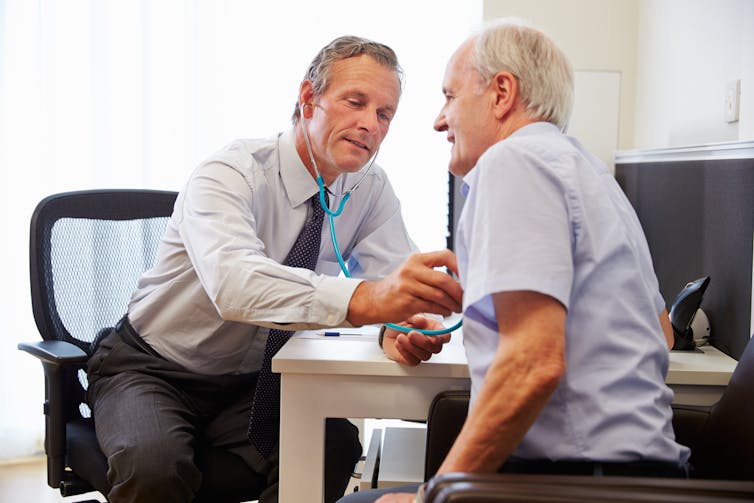 Older doctor treats older patient