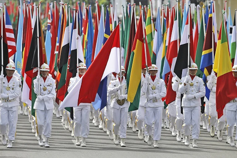 Soldiers lead an honour guard carrying numerous flags of countries from the global South.