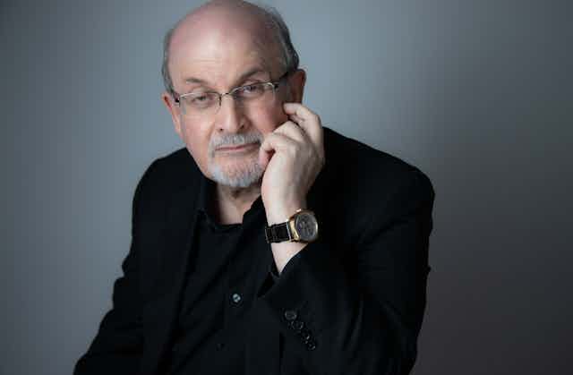 Salman Rushdie poses in an all-black suit.