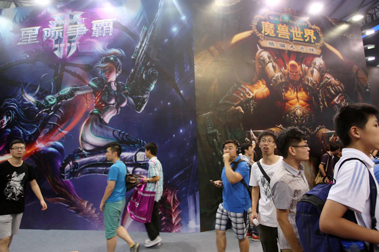 Young boys stand in front of large-scale posters for a video game.