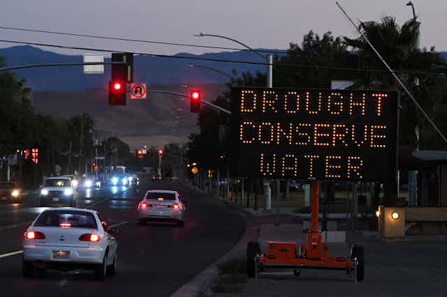 A sign bordering a highway reads "Drought Conserve Water"