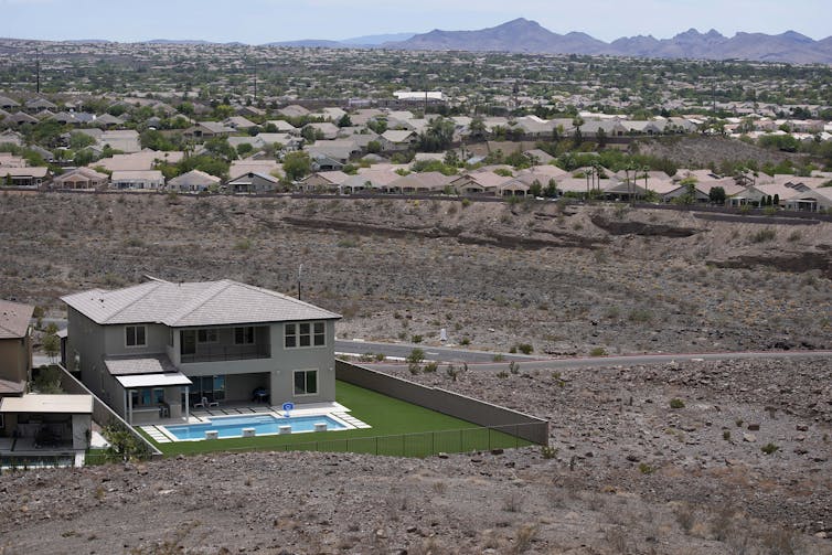 A large house with a pool, bordered by brown dirt