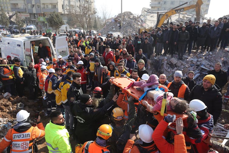A little girl is carried on a stretcher to a waiting ambulance surrounded by rescue workers.