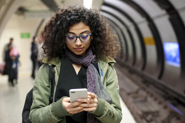 A young woman checks her cell phone in a European subway.