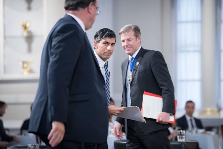 Three men in suits talking and smiling