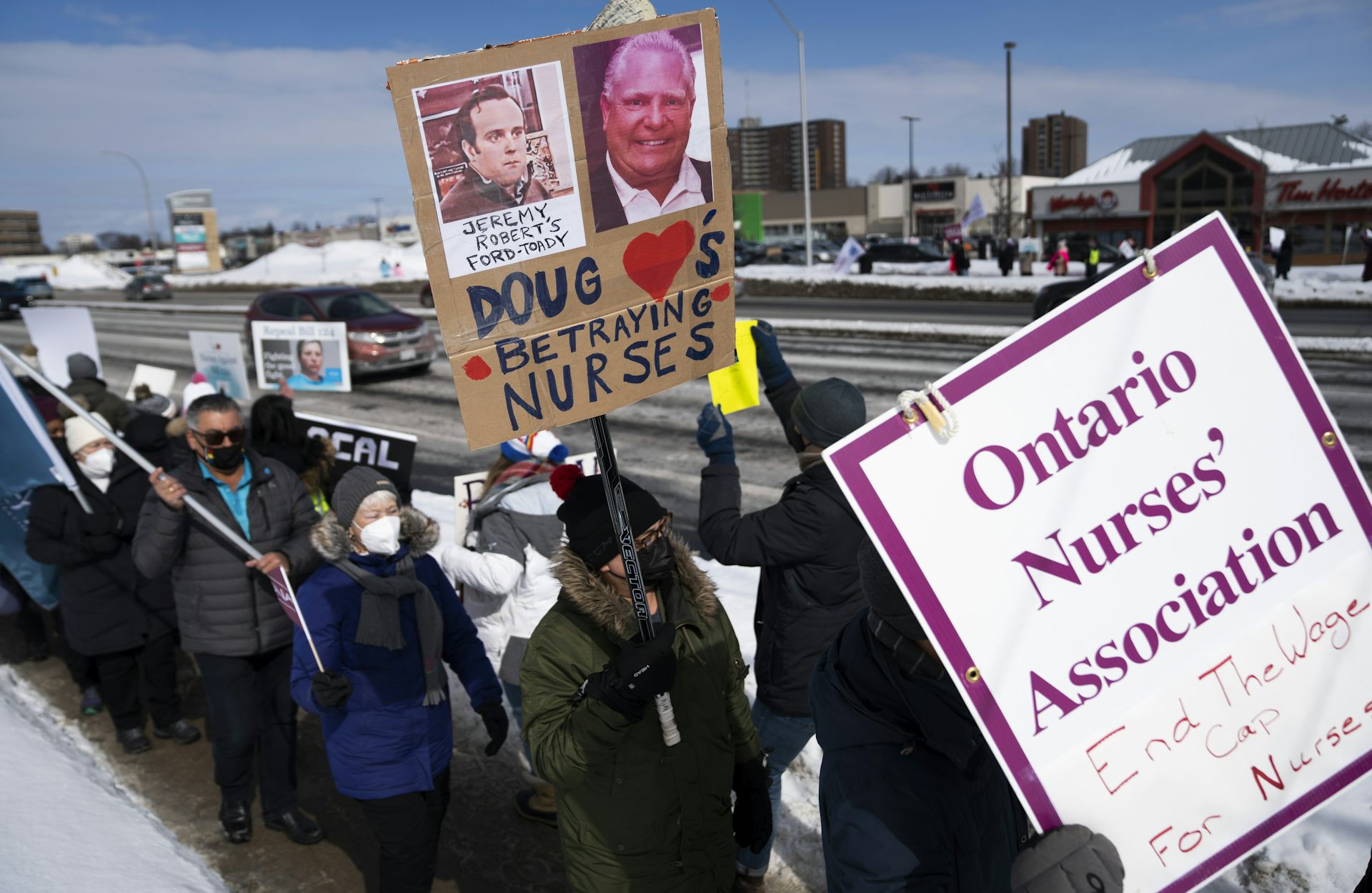 A line of protesters behind an 'Ontario Nurses' Association' placard