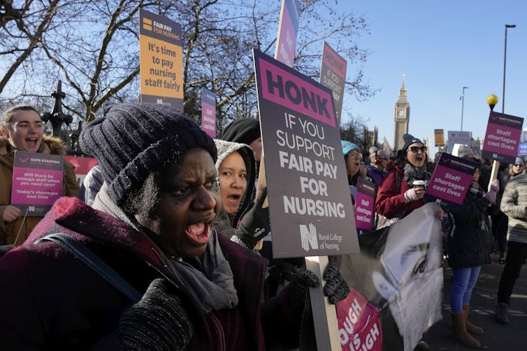 A crowd of protesters with signs supporting fair pay for nurses