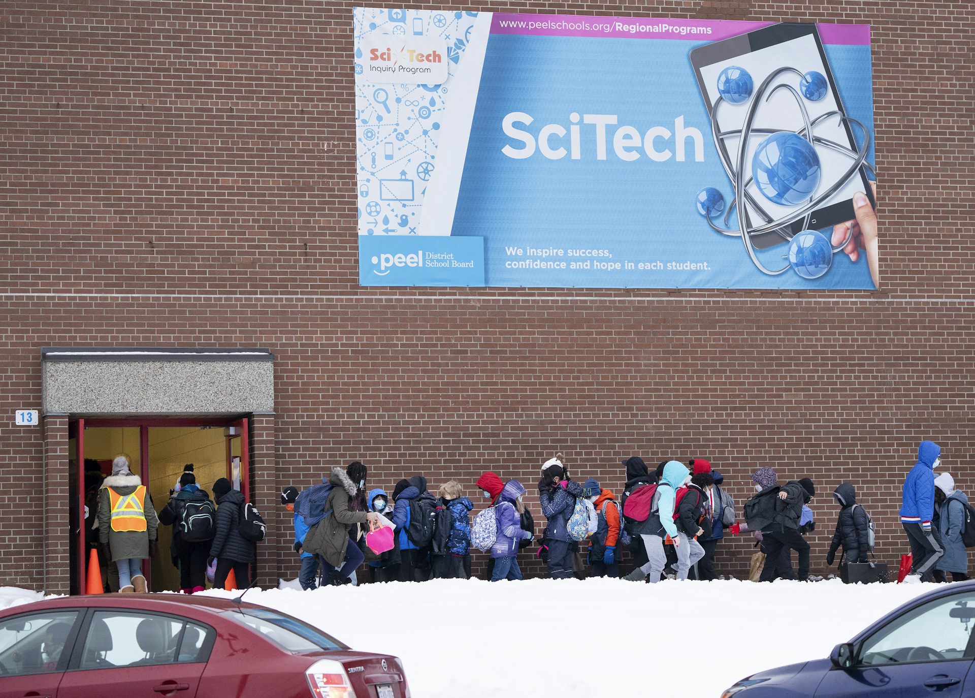 Students seen standing outside in a line waiting to go into school.