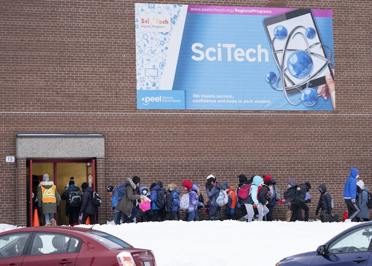 Students seen standing outside in a line waiting to go into school.
