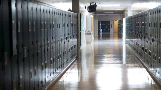 A long hallway is seen with lockers on both sides.