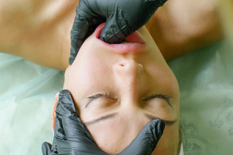 Beauty therapist performing buccal massage on woman
