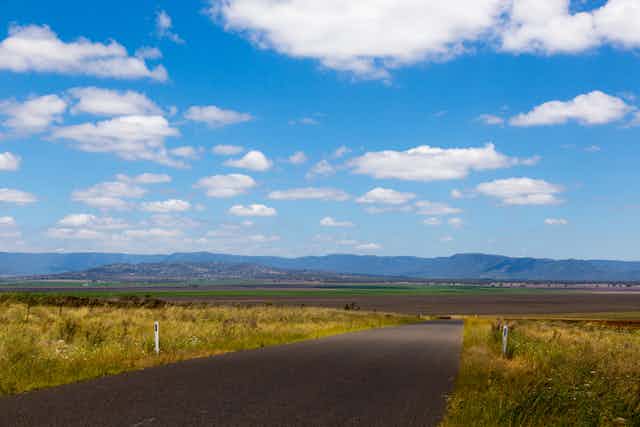 road through grasslands with mountains in the distance