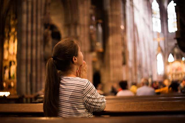 A young woman praying in a pew in a church