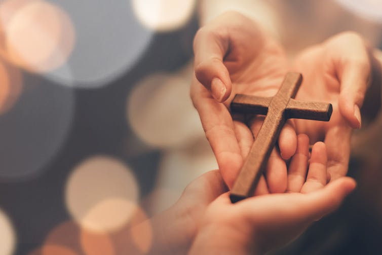 A woman's hands holding a wooden cross