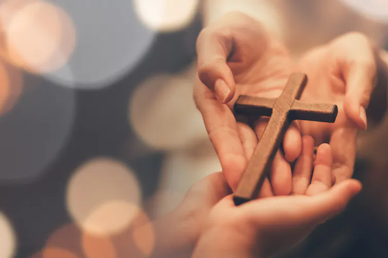 A woman's hands holding a wooden cross