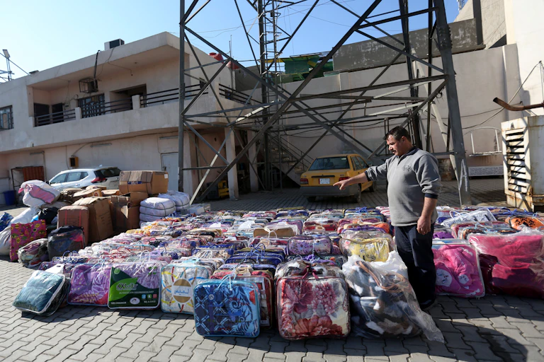 A man gestures at stacks of packages of aid for earthquake victims in Syria.