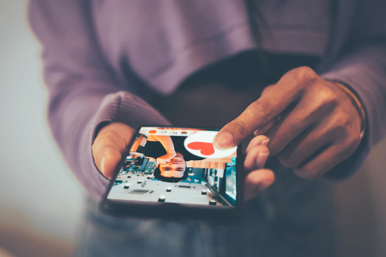 Close up of a woman's hands holding a phone and swiping on a man's profile on a dating app