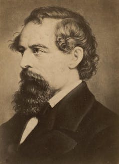 A sepia side profile portrait of Charles Dickens. He has a beard which covers only his chin and not his jawline.
