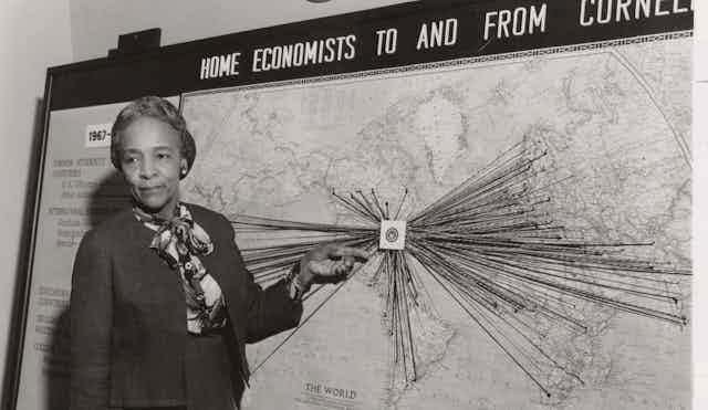 A woman stands in front of a map