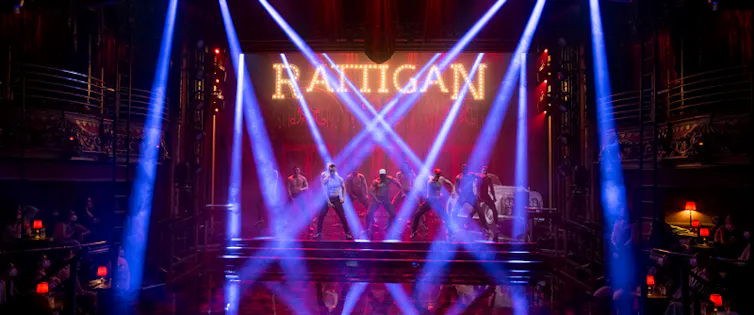 A row of topless men pose under strobe lights.