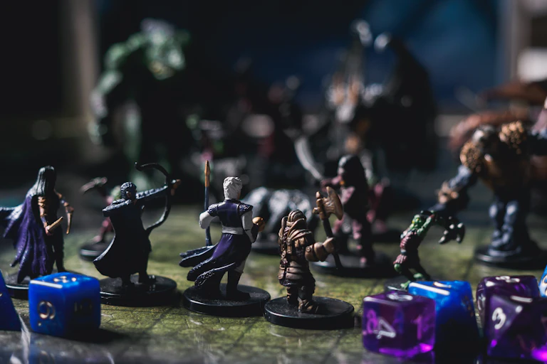 Mini figurines of fantasy characters sit on a tabletop game board. In the background, monster figures sit on the board, facing the fantasy character figurines.