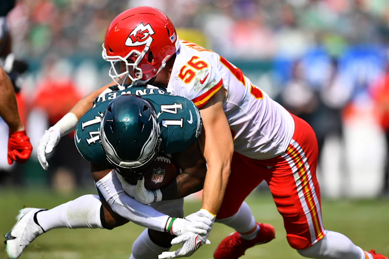 A football player in a Kansa City helmet tackles another athlete in a green Philadelphia jersey
