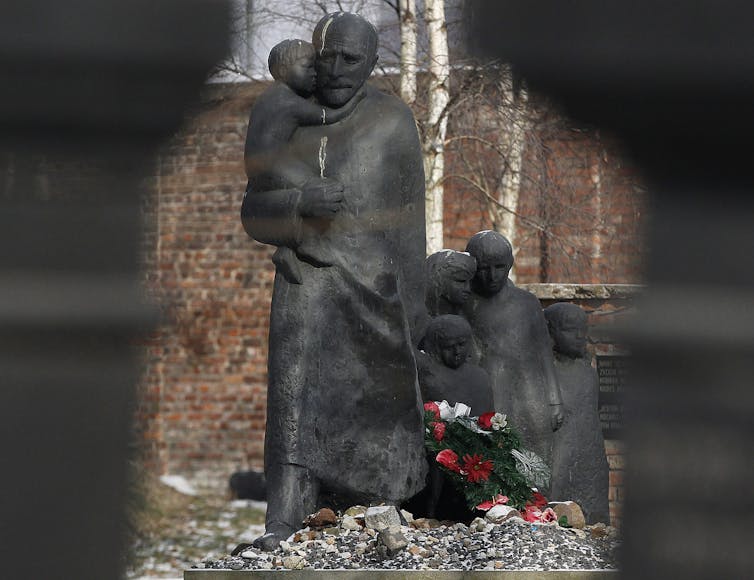 A statue of a man carrying a child with other children following behind.