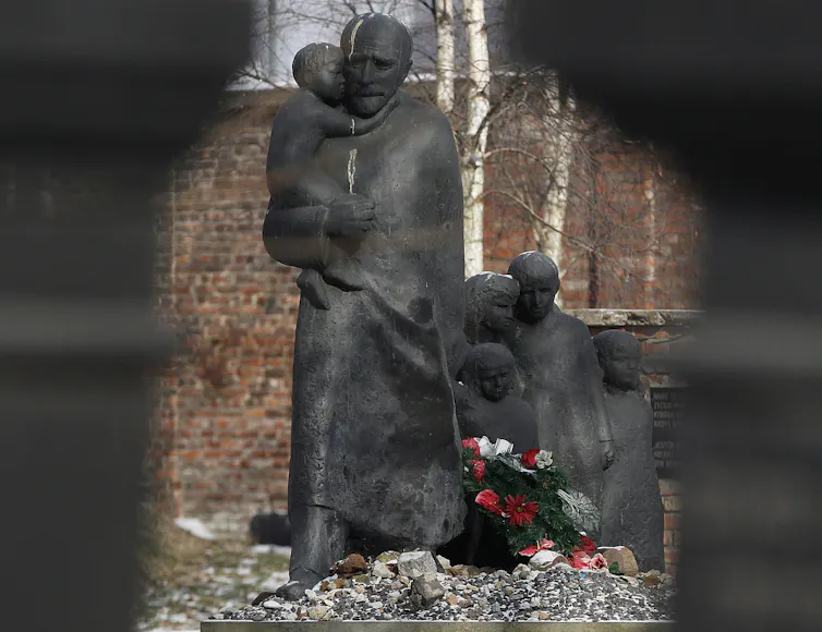 A statue of a man carrying a child with other children following behind.